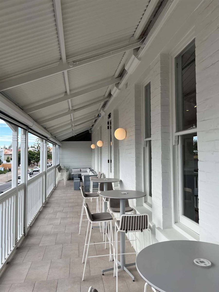 Upstairs hotel balcony with round globe wall lights along white painted brick