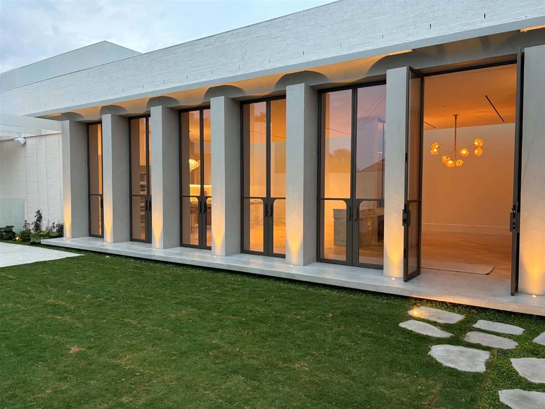 Modern home at dusk with uplights on each column and lights set into the garden path