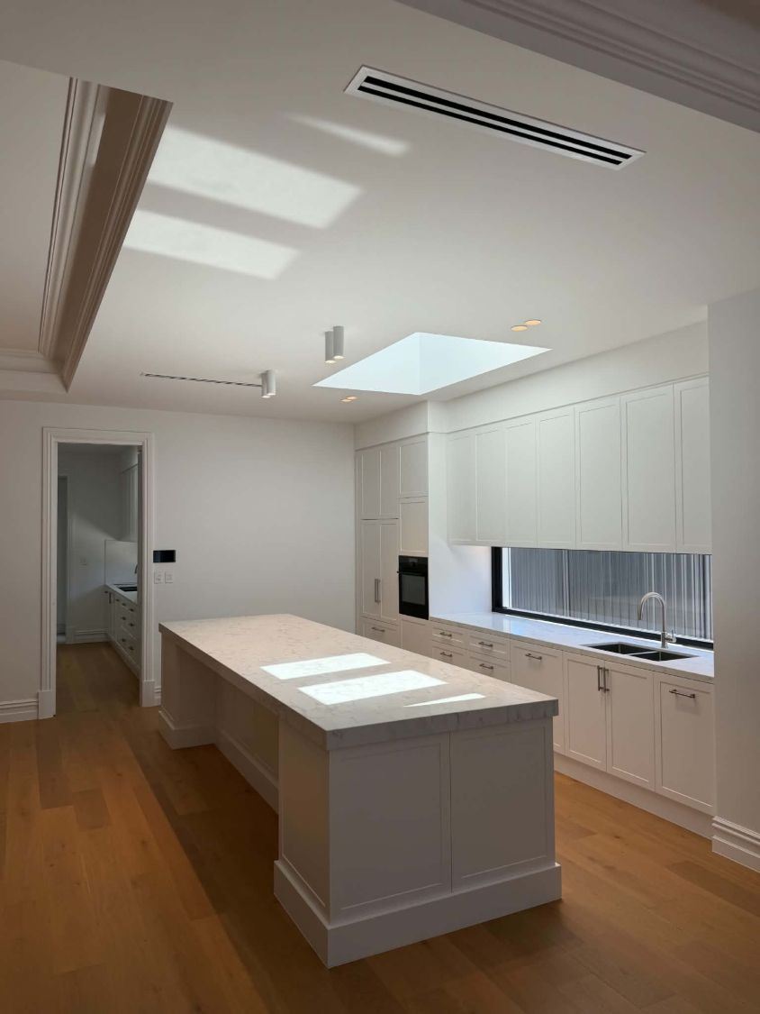 White kitchen with downlights, track lights and a skylight above the island