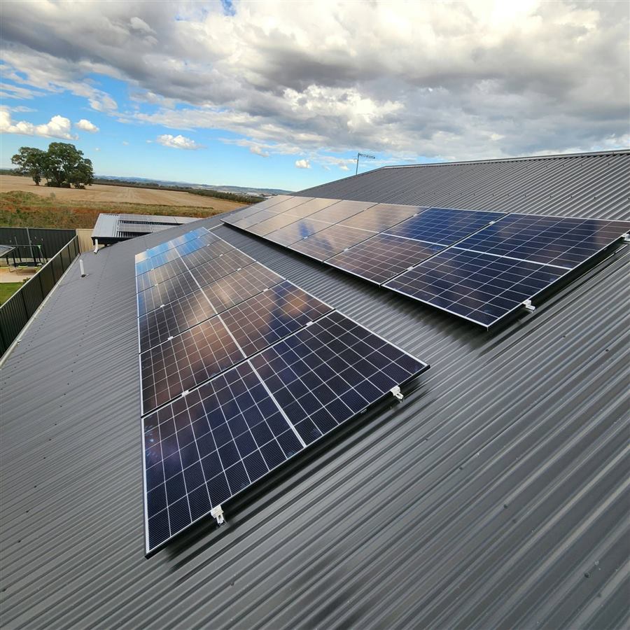 Solar panels on a dark corrugated roof overlooking farmland